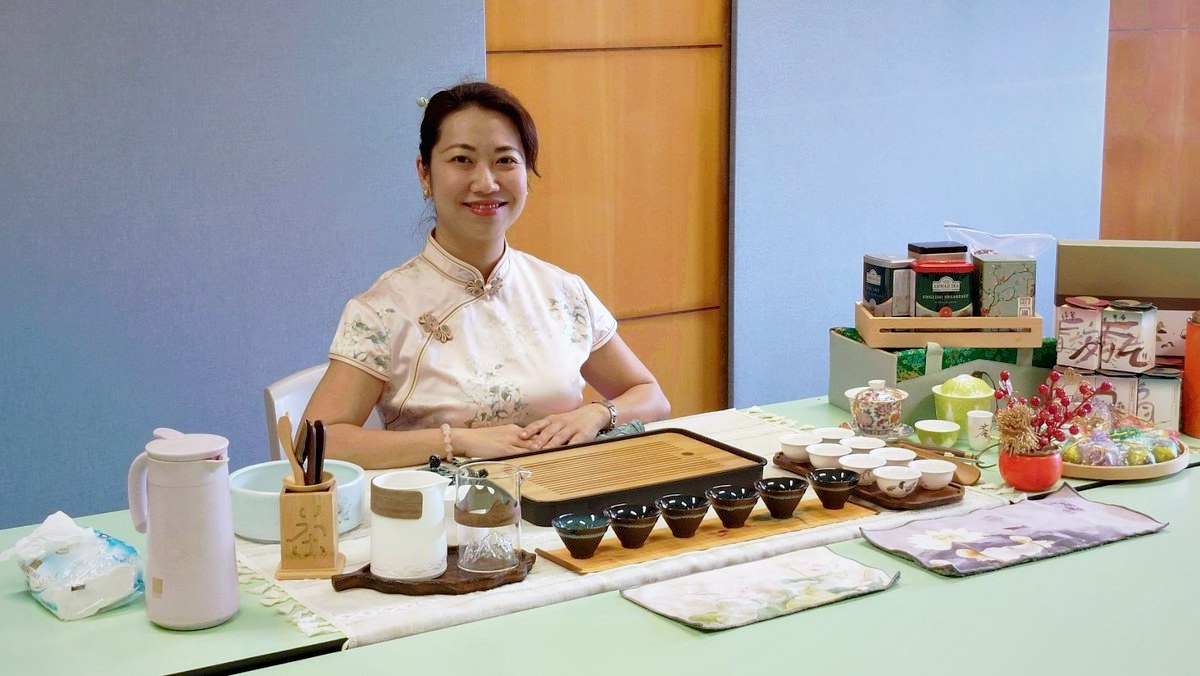 本會導師穿著旗袍，坐在佈置好的茶席前準備茶藝工作坊
